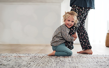 Image showing Happy, child clinging to leg of woman and playful fun and smile on carpet in home with mother. Little girl playing, laughing and joking with happiness, mom in pajamas and trust on floor in apartment.