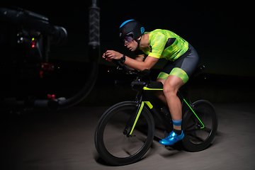 Image showing A videographer recording a triathlete riding his bike preparing for an upcoming marathon.Athlete's physical endurance and the dedication required to succeed in the sport.