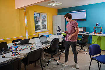 Image showing A student testing his new invention of a robotic arm in the laboratory, showcasing the culmination of his research and technological prowess.