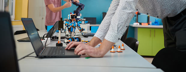 Image showing A student testing his new invention of a robotic arm in the laboratory, showcasing the culmination of his research and technological prowess.