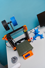 Image showing Modern 3d printer for creating 3d models and materials on the table in the laboratories next to the computer