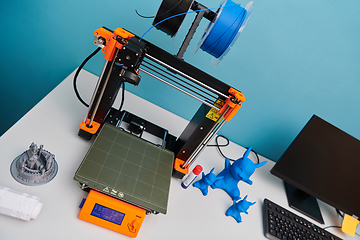 Image showing Modern 3d printer for creating 3d models and materials on the table in the laboratories next to the computer