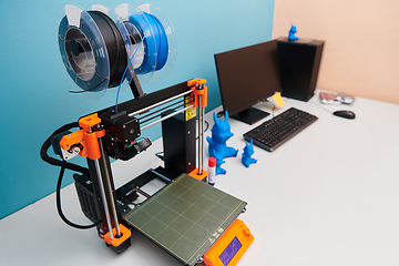 Image showing Modern 3d printer for creating 3d models and materials on the table in the laboratories next to the computer