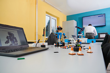 Image showing A student testing his new invention of a robotic arm in the laboratory, showcasing the culmination of his research and technological prowess.