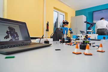 Image showing A student testing his new invention of a robotic arm in the laboratory, showcasing the culmination of his research and technological prowess.