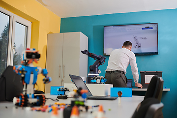 Image showing A student testing his new invention of a robotic arm in the laboratory, showcasing the culmination of his research and technological prowess.