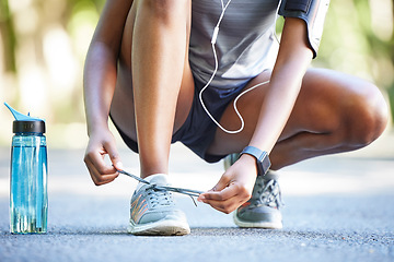 Image showing Water, bottle and athlete tie laces ready to exercise, workout or fitness outdoors in a park by female training. Active, fit and closeup of person or runner preparing to jog for health and wellness