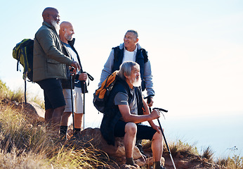 Image showing Senior, men and hiking in nature, relax and calm, sitting and happy on blue sky background. Elderly, friends and man hiker group bond on hill top, freedom and exercise, fitness or retirement activity