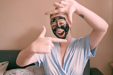 Image showing Self care, face mask and funny woman in her home, house or apartment doing morning beauty routine and hand gesture. Portrait, relax and female taking picture frame or sign for skincare using charcoal
