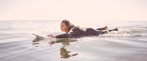 Image showing Surfer, woman and swimming in waves, sea and ocean for summer adventure, freedom and sky mockup. Female surfing on board in water, beach and relax for tropical holiday, nature travel and peace sports