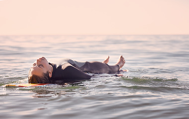 Image showing Surfing, woman and lying on board in waves, sea and ocean for summer adventure, freedom and sky background. Calm female surfer relax in water, beach and swimming for tropical holiday, travel or peace