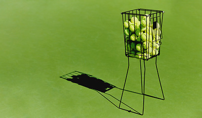 Image showing Tennis, sport ball basket of sports field on a green training court outdoor with no people. Exercise, fitness and workout equipment shadow for match of game competition on turf ground with mockup