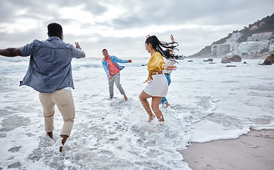 Image showing Friends at beach, water splash and ocean with travel and adventure, group of people have fun on holiday. Diversity, playful and nature, social get together and laugh, freedom outdoor in Los Angeles