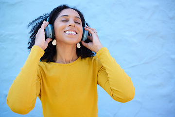 Image showing Headphones, black woman and happy music on wall background, blue backdrop and mockup. Excited girl listening to radio, podcast and sound of streaming, audio and face of smile, relax and hearing tech