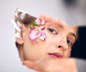 Image showing Portrait, skincare and woman with reflection, flower and cosmetics on grey studio background. Face, female and lady with mirror, plants and floral for decoration, makeup and natural dermatology