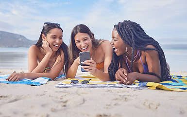 Image showing Girl friends, beach and phone of a teenager laughing at funny meme by the sea in Miami. Travel, vacation and sunshine with happy students enjoying spring break with mobile connection lying on sand