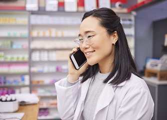 Image showing Pharmacy, phone and healthcare worker talking with a mobile connection at work. Asian woman, pharmacist and business communication of a dispensary employee with a smile from conversation in store