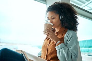 Image showing Airport, coffee and black woman reading a book by window waiting for global flight, departure and travel. International transport, lobby and girl with headphones for music, drinking beverage and read