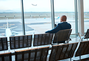 Image showing Waiting, airport and black man on a phone rest for travel, plane and air flight. Businessman, mobile connection and person sitting with cellphone looking at traveler app info for airplane traveling