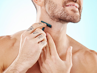 Image showing Hands, shaving and beard with a man grooming in studio on a blue background for skincare or hygiene. Shave, tattoo and neck with a male in the bathroom for hair removal as part of a morning routine
