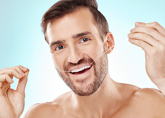 Image showing Face, portrait and man with dental floss in studio isolated on a blue background. Oral health, hygiene or happy male model flossing teeth for wellness, cleaning or fresh breath, cosmetics or gum care