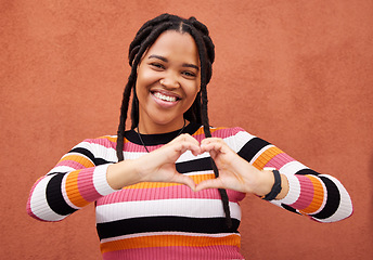 Image showing Happy, heart and portrait black woman by a wall in the city while on a walk on a weekend trip. Happiness, smile and African female with a love emoji or hand gesture in town on holiday or vacation.