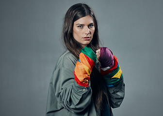 Image showing Woman, fists and pride colors in protest for gay, LGBTQ or human rights against gray studio background. Portrait of female activist standing ready in fighting pose for equality or sexuality on mockup