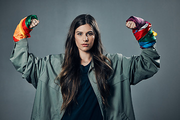 Image showing Woman, protest and rainbow fists for gay, LGBTQ or human rights against a gray studio background. Portrait of female activist standing ready in fighting flex for equality, empowerment or sexuality