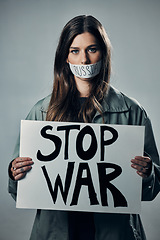 Image showing War, stop and portrait of a woman with a sign while silent isolated on a grey studio background. Protest, crime and silenced girl with a board against conflict and violence in Russia on a backdrop