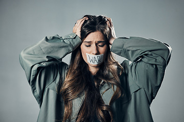 Image showing Woman, protest and tape on mouth in fear for cold war, armageddon or doomsday against gray studio background. Female activist with hands on head and message to stop or end global violence in society