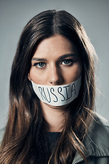 Image showing Woman, face and protest with mouth tape in Russia for cold war, armageddon or doomsday against a gray studio background. Portrait of female activist or secret Russian agent or refugee in silence