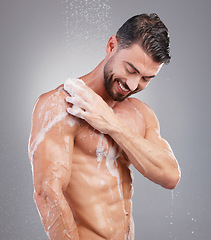 Image showing Shower, sponge and man with water in studio on gray background for wellness, grooming and beauty. Skincare, bathroom hygiene and happy male smile for washing body, cleaning and soap for healthy skin