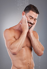 Image showing Shower, cleaning and man with water in studio on gray background for wellness, grooming and beauty. Skincare, bathroom hygiene and male smile for washing body, clean face and soap for healthy skin