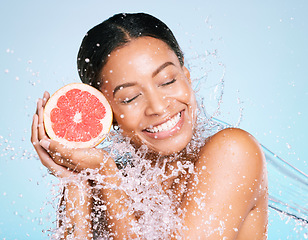 Image showing Grapefruit, beauty and skin care of a woman for healthy skin and diet on a blue background. Face of aesthetic model person with water splash and fruit for sustainable facial health and wellness