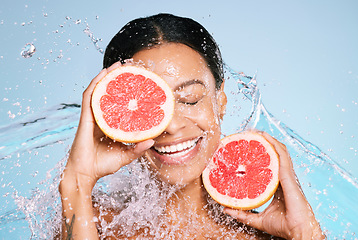 Image showing Beauty, grapefruit and skin care with a woman for healthy skin and diet on a blue background. Face of aesthetic model person with water splash and fruit for sustainable facial health and wellness