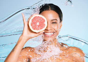 Image showing Beauty, skin care and woman portrait with a grapefruit for healthy skin and diet on blue background. Face of aesthetic model person water splash and fruit for sustainable facial health and wellness