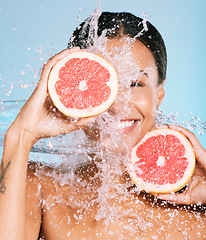 Image showing Water splash, skin care and woman with a grapefruit for healthy skin and diet on blue background. Face of aesthetic model person with beauty smile and fruit for sustainable facial health and wellness