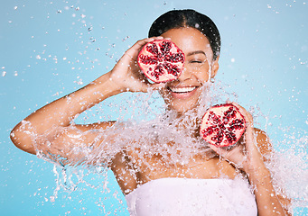 Image showing Beauty, skin care and woman with a pomegranate for healthy skin and diet on a blue background. Face of aesthetic model person with water splash and fruit for sustainable facial health and wellness