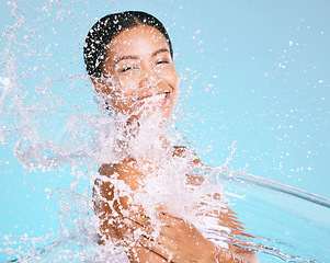 Image showing Water, splash and black woman cleaning her body for beauty, skincare and self care isolated in studio blue background. Portrait, model and young female washing skin for hygiene, aqua and hydration