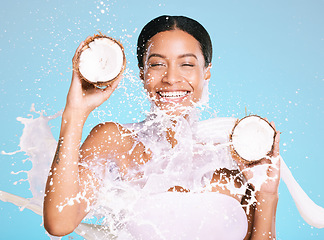 Image showing Beauty, skin care and woman with coconut for healthy skin and diet on a blue background. Face of happy aesthetic model person with milk splash and fruit for sustainable facial health and wellness