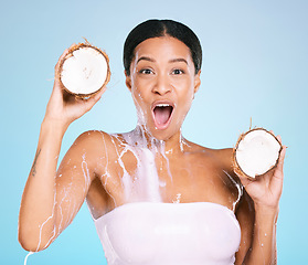 Image showing Beauty, wow and woman portrait with a coconut for healthy skin and diet on a blue background. Face of shocked model person with milk splash and fruit for sustainable facial health and wellness