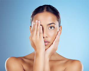 Image showing Portrait, hands and woman cover face for beauty, studio and skincare cosmetics on blue background. Female model, facial and dermatology transformation of healthy aesthetic, laser and natural shine