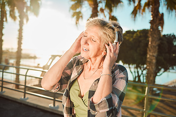 Image showing Happy, music and singing with old woman at beach for streaming, freedom and summer break. Internet, technology and headphones with senior lady listening to online radio for podcast, audio and media