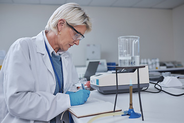 Image showing Science, research and woman writing notes or data in notebook with burner experiment on desk. Healthcare, innovation and female scientist working on vaccine manufacturing and future medical analytics