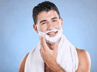 Image showing Shaving foam on beard, smile and hand on face with towel and product placement in studio mock up. Shave cream, facial and hair or skincare for happy male model grooming, isolated on blue background.