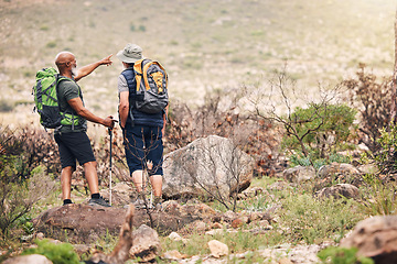 Image showing People, friends and hiking on mountain pointing with backpack for travel, adventure or trekking in nature. Hiker men with stick standing on rock together for traveling trail or backpacking outdoors