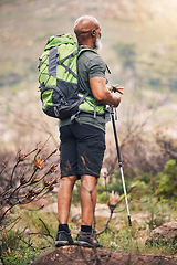 Image showing Black man, hiking and mountain with backpack for travel, adventure or trekking in the nature. African American male hiker with stick standing on rock for traveling or backpacking in the outdoors