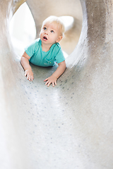 Image showing Child playing on outdoor playground. Toddler plays on school or kindergarten yard. Active kid on stone sculpured slide. Healthy summer activity for children. Little boy climbing outdoors.