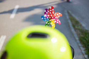 Image showing Colorful pinwheel attached to bicycle basket to entertain toddler child riding on front child seat on bike in summer.