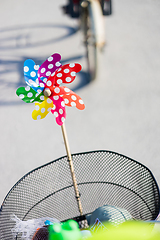 Image showing Colorful pinwheel attached to bicycle basket to entertain toddler child riding on front child seat on bike in summer.